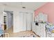 Bright bedroom with a pink accent wall, white dresser, and a closet, creating a playful and inviting space at 43825 State Road 19, Altoona, FL 32702