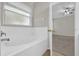 Bright bathroom featuring a soaking tub with tile surround and a view into the main bedroom at 530 Hiawatha Palm Pl, Apopka, FL 32712