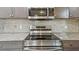 A close-up view of the stainless steel range, microwave, and gray cabinets with granite countertops in the kitchen at 6148 Landrace Ln, Orlando, FL 32807