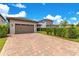 Paver driveway leading to a two-car garage, surrounded by lush landscaping at 9544 Mere Pkwy, Orlando, FL 32832