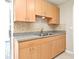 Kitchen featuring tan cabinetry, stainless steel sink, decorative backsplash, and backyard patio access at 994 Lormann Cir, Longwood, FL 32750