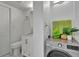 Clean bathroom features a modern vanity, toilet, and a stacked washer-dryer with decorative accents on top at 100 S Interlachen Ave # 410F, Winter Park, FL 32789
