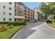 Exterior view of the building with parking area, complemented by lush landscaping and vibrant flower beds at 100 S Interlachen Ave # 410F, Winter Park, FL 32789