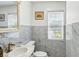 Elegant half bath featuring marble tile, modern fixtures, and natural light from the window at 1002 Lake Elbert Se Dr, Winter Haven, FL 33880