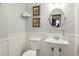 Charming powder room featuring beadboard walls, pedestal sink, and decorative artwork at 1002 Lake Elbert Se Dr, Winter Haven, FL 33880