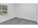 This bedroom features gray hardwood floors and a bright window overlooking lush outdoor scenery at 13430 Sw 88Th Ter, Ocala, FL 34473