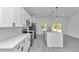 Bright kitchen features stainless appliances, white cabinets and a large island with granite countertops and modern pendant lighting at 13430 Sw 88Th Ter, Ocala, FL 34473