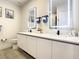 Modern bathroom featuring dual sinks, white cabinets, illuminated mirrors, and gray flooring at 17230 Blessing Dr, Clermont, FL 34714