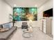 Cozy living room features a vibrant mural, gray sofa, and round glass coffee table at 17230 Blessing Dr, Clermont, FL 34714