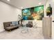 Comfortable living room featuring a sofa, side chair, glass tables and a cartoon mural at 17230 Blessing Dr, Clermont, FL 34714