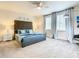 Main bedroom featuring a tufted headboard, gray nightstands, two windows with gray curtains, and modern lamps at 17230 Blessing Dr, Clermont, FL 34714