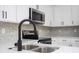 Modern kitchen with a sleek black faucet, stainless steel appliances, and unique backsplash at 2041 Warrens Ave, Maitland, FL 32751