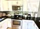 Modern kitchen with stainless steel appliances, mosaic backsplash, and white cabinets for an inviting space at 213 S Lake Pleasant Rd, Apopka, FL 32703