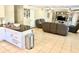 Open-concept view of the living room and kitchen featuring tile floors, an entertainment center, and grey recliners at 213 S Lake Pleasant Rd, Apopka, FL 32703