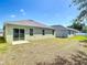 This view showcases the backyard with a sliding glass door, small patio, and partial lawn at 2312 Rose Blvd, Winter Haven, FL 33881