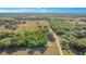 Expansive aerial view of a home, buildings, pastures and surrounding tree lines at 36208 Micro Racetrack Rd, Fruitland Park, FL 34731