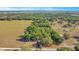 Aerial view of property featuring a large field, mature trees, outbuildings, and a single-story home at 36208 Micro Racetrack Rd, Fruitland Park, FL 34731
