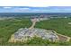 An aerial view captures houses nestled near a tranquil pond and forest with city views beyond at 4296 Mirror Ct, Clermont, FL 34714