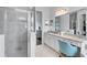 Elegant bathroom with a glass-enclosed shower, double vanity, and a stylish makeup area with a comfortable chair at 4296 Mirror Ct, Clermont, FL 34714