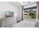 A well-lit bedroom with a large window, TV, and dresser at 4296 Mirror Ct, Clermont, FL 34714