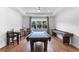 Spacious game room features a pool table, shuffleboard, wood floors, and a large window at 4296 Mirror Ct, Clermont, FL 34714