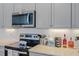 Modern kitchen featuring stainless steel appliances, sleek backsplash, and grey cabinets at 4296 Mirror Ct, Clermont, FL 34714