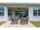 Covered patio with comfortable seating and view to the backyard and a sliding glass door at 4296 Mirror Ct, Clermont, FL 34714