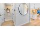 Bright hallway featuring modern finishes, a round mirror, and an open view into the adjacent dining area at 5156 Gardenrow Dr, St Cloud, FL 34772