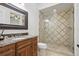 Bathroom with dark wood vanity, marble countertop, decorative mirror, and tiled glass shower at 5550 Osprey Isle Ln, Orlando, FL 32819