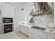 Modern white kitchen featuring updated stainless appliances, a stylish range hood, and marble countertops at 5550 Osprey Isle Ln, Orlando, FL 32819
