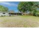 View of the spacious backyard with a screened lanai and lush green surroundings at 735 Baltimore Dr, Orlando, FL 32810
