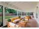 An outdoor patio featuring natural sunlight, comfortable seating, and a view of the yard beyond the screen at 735 Baltimore Dr, Orlando, FL 32810