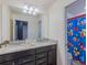 Bathroom featuring a double vanity with granite countertop and Mickey Mouse themed shower curtain at 880 Paradise Dr, Davenport, FL 33897