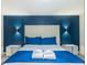 Modern bedroom with a blue accent wall, plush bed, stylish lighting, and nightstands at 880 Paradise Dr, Davenport, FL 33897