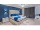 Modern bedroom with a blue accent wall, plush bed, stylish lighting, and gray curtains at 880 Paradise Dr, Davenport, FL 33897