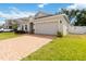 Well maintained single-story home with brick driveway, two car garage, landscaped yard and white vinyl fence at 928 Avenal Ln, Davenport, FL 33837