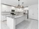 Modern kitchen boasts white cabinets, stainless steel appliances, a large island with a breakfast bar, and ample lighting at 928 Avenal Ln, Davenport, FL 33837