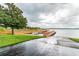 Wooden boat dock and ramp extending into the lake with mature trees and grass on either side at 13241 Fountainbleau Dr, Clermont, FL 34711