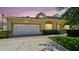 Inviting home with a two-car garage, well-maintained lawn, and a welcoming entrance at sunset at 13241 Fountainbleau Dr, Clermont, FL 34711