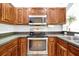 This kitchen features wooden cabinets, stainless steel appliances, and granite countertops at 10374 Park Commons Dr, Orlando, FL 32832