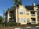 Charming yellow condo building with stairs, balconies, a mature palm tree, and well-maintained landscaping at 1079 S Hiawassee Rd # 1121, Orlando, FL 32835