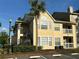 Charming yellow condo building with stairs, balconies, a mature palm tree, and well-maintained landscaping at 1079 S Hiawassee Rd # 1121, Orlando, FL 32835