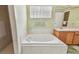Bright bathroom with soaking tub, glass block window, tile surround, and wooden cabinets at 1156 Brandy Lake View Cir, Winter Garden, FL 34787