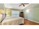 A main bedroom with neutral bedding, wood floors, ceiling fan, and a view of the window at 1156 Brandy Lake View Cir, Winter Garden, FL 34787