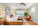 A well-lit main bedroom with wooden floors, a ceiling fan, and a tufted headboard bed, complemented by colorful accents and a sitting area at 1156 Brandy Lake View Cir, Winter Garden, FL 34787