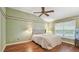 This main bedroom features hardwood floors, a ceiling fan, a queen bed, and a large window at 1156 Brandy Lake View Cir, Winter Garden, FL 34787