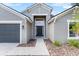 A home's front entrance with a gray garage door and a black front door flanked by neatly arranged landscaping at 119 Argyle Gate Loop Rd, Dundee, FL 33838
