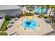 Aerial view of a splash pad and pool with lounge chairs and tables under umbrellas at 13864 Destin Beach Ln, Orlando, FL 32827