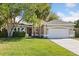 Charming single-story home with a well-manicured lawn, mature trees, and an attached two-car garage at 14841 Faversham Cir, Orlando, FL 32826