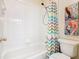 Bright bathroom featuring a shower and tub combo with a colorful shower curtain and decorative wall art at 16604 Caribbean Breeze Way, Clermont, FL 34714